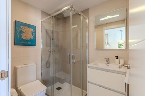 A modern bathroom with a glass-enclosed shower, a white toilet, a sink with a mirror, and a map of Madrid on the wall. - Bright and Fantastic Studio - Apartment Puerta Toledo (Madrid)