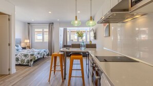 Una cucina moderna con isola centrale, sgabelli in legno e illuminazione a sospensione.