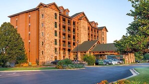 A multi-story hotel with a stone facade, a covered entrance, and a parking lot.