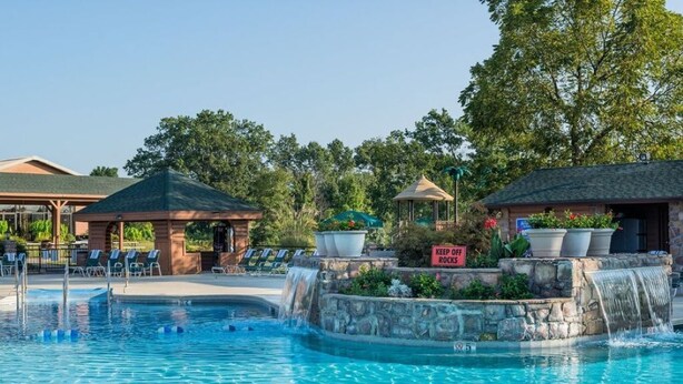 A swimming pool with lounge chairs, a gazebo, and a waterfall feature.