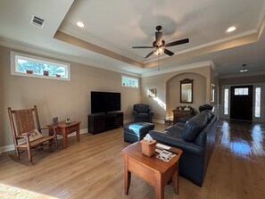 A spacious living room with a ceiling fan, a television, a sofa, a rocking chair, and a wooden coffee table.
