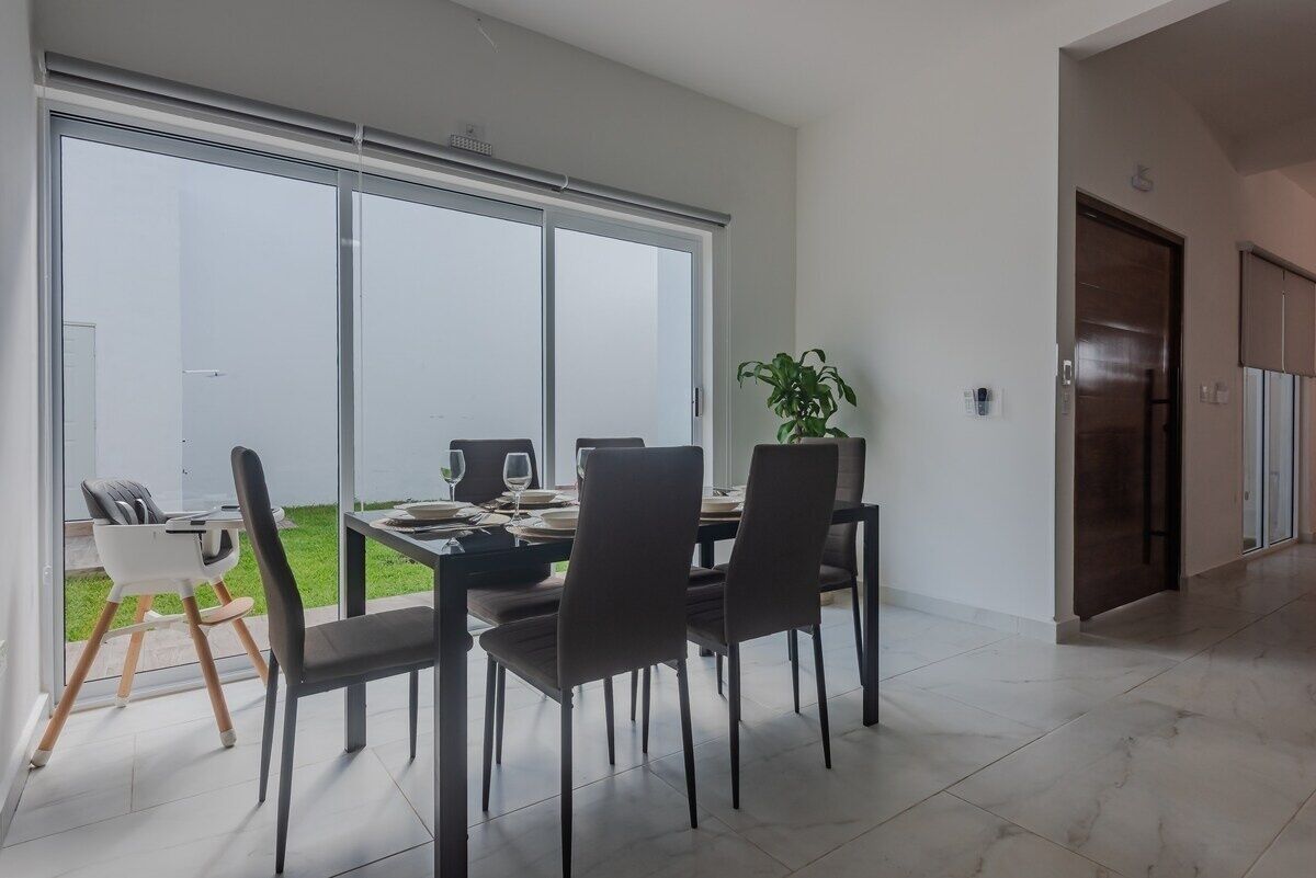A dining area with a large sliding glass door, a dining table set for four, and a potted plant.