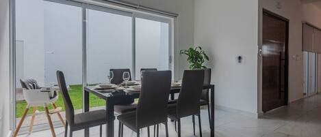 A dining area with a large sliding glass door, a dining table set for four, and a potted plant.