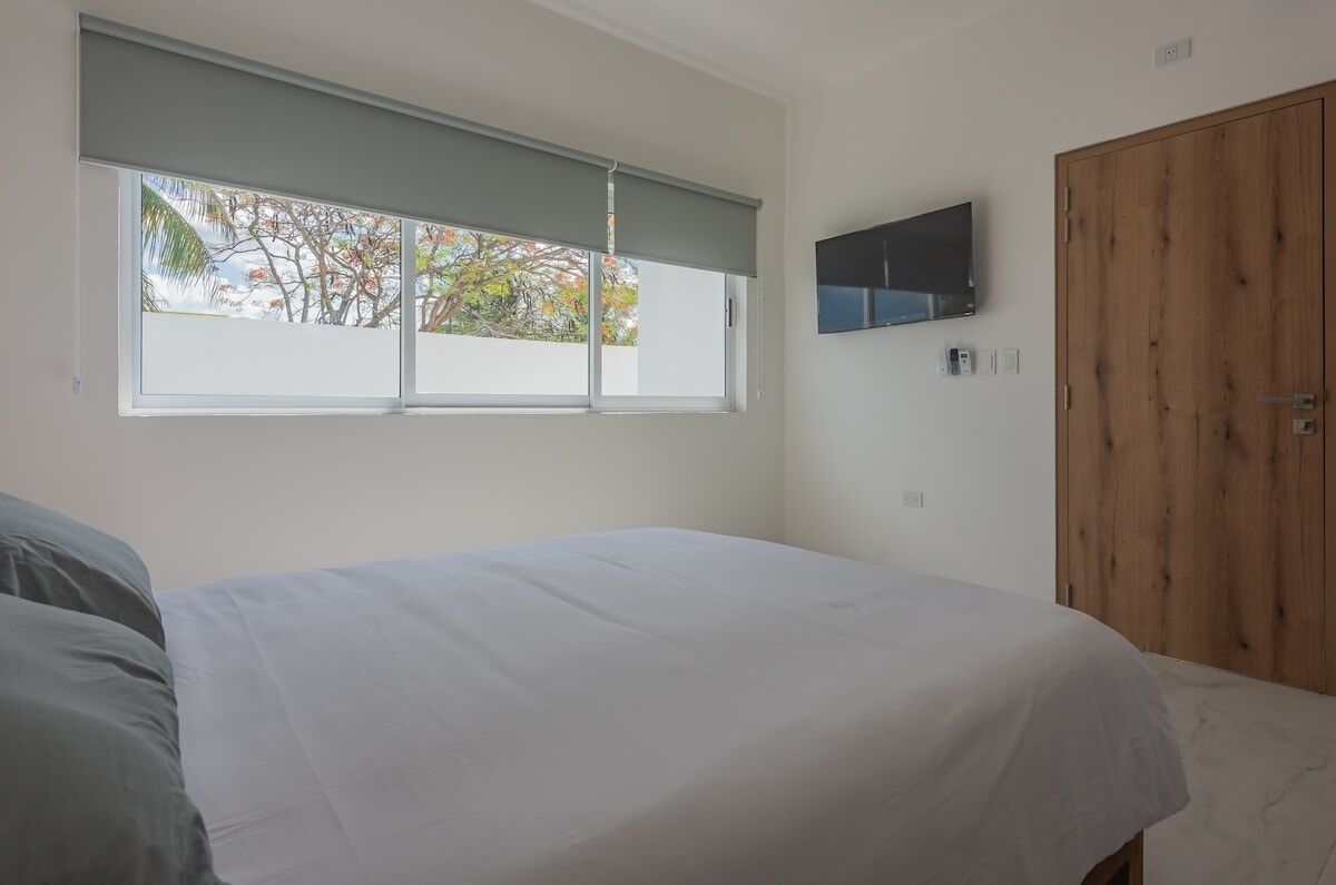 Une chambre à coucher avec un lit, une fenêtre donnant sur un beau paysage, une télévision et une armoire en bois.