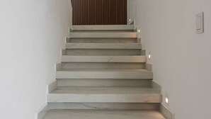 Eine Treppe mit weißen Stufen und einer Holzwand oben.