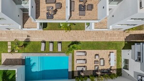 Ein modernes Gebäude mit Pool auf dem Dach, Sitzgelegenheiten im Freien und einem gepflegten Rasen.