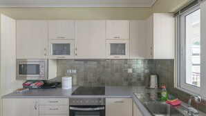 Cozinha moderna com eletrodomésticos de aço inoxidável, um micro-ondas e uma janela que proporciona iluminação natural.