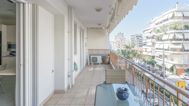Uma varanda com mesa, cadeiras e vista para a cidade.