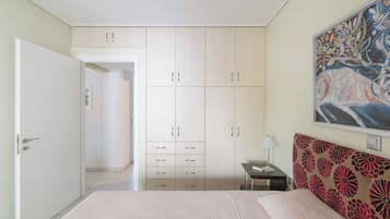 Ein Schlafzimmer mit einem Bett, einem Kleiderschrank, einem Nachttisch, einer Lampe und einem Bild an der Wand.