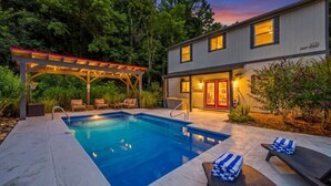 A modern house with a swimming pool, outdoor seating, and a covered patio.
