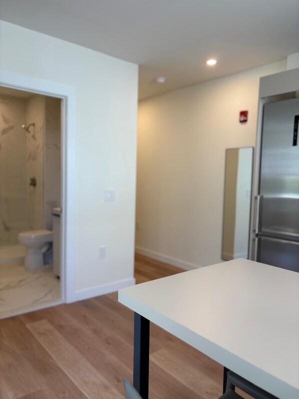 A modern kitchen with a stainless steel refrigerator, a white countertop, and a wooden floor. - 101 Wave Miami Beach (Miami Beach)