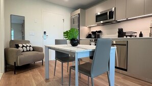 A modern kitchen with a dining area, a sofa, and a potted plant. - 101 Wave Miami Beach (Miami Beach)