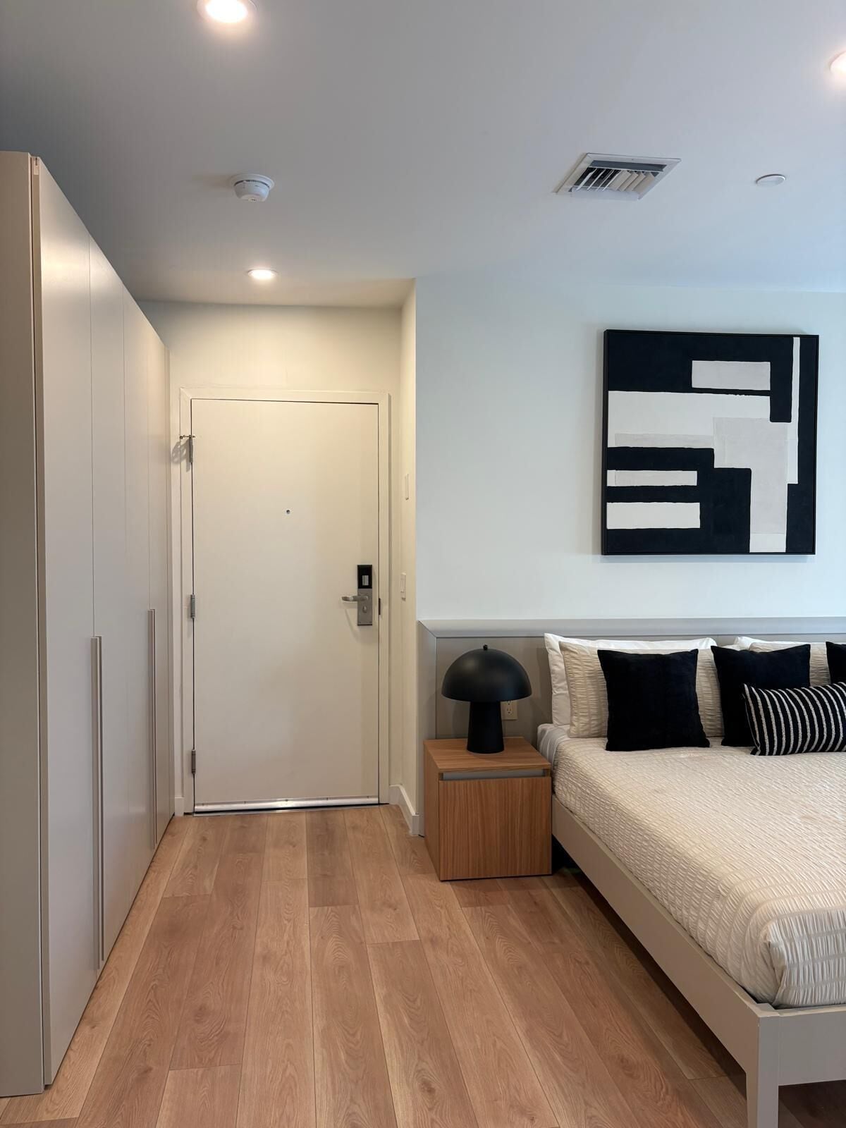 A bedroom with a bed, bedside table, lamp, and a door.