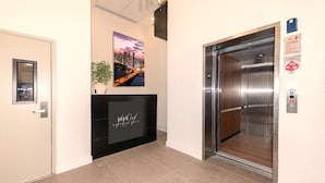 A hotel lobby with a reception desk, an elevator, and a cityscape painting on the wall. - 101 Wave Miami Beach (Miami Beach)
