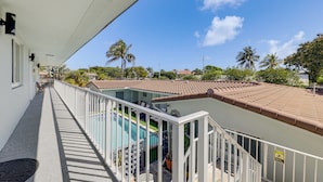 Ein Balkon mit Pool, weißen Geländern und einem Ziegeldach.