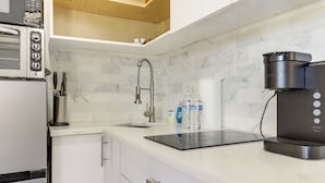 Eine Küche mit integriertem Mikrowellenherd, einer Kaffeemaschine und einem Wasserspender auf der Arbeitsfläche.