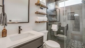 A modern bathroom with a glass shower enclosure, a white sink, and a large mirror.