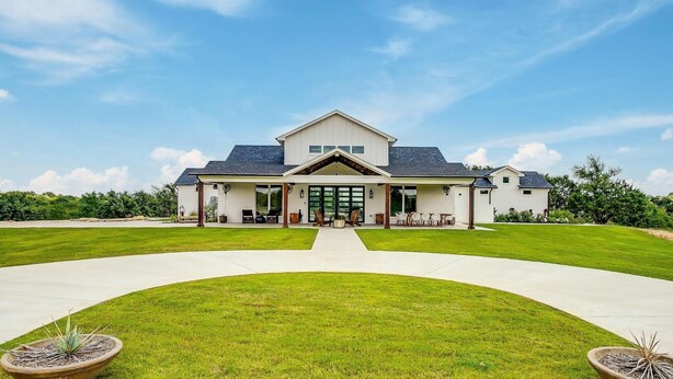 A modern two-story house with a covered patio, a front lawn, and a driveway leading to the entrance.