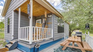 Une cabane avec une véranda, une table et un barbecue.
