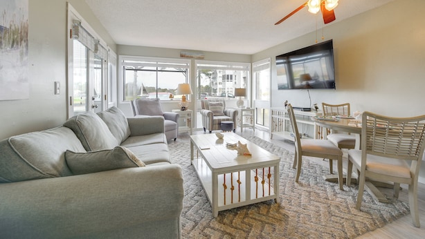 A living room with a sofa, coffee table, dining table, chairs, and a ceiling fan. - Coastal Sun & Poolside Fun: Myrtle Beach Condo! (Myrtle Beach)
