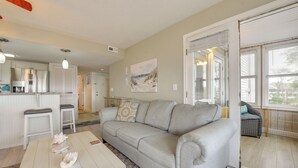 A living room with a grey sofa, white coffee table, and a painting on the wall. - Coastal Sun & Poolside Fun: Myrtle Beach Condo! (Myrtle Beach)