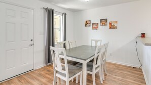En matplats med ett bord och stolar, en vit dörr och en vägg med inramade tavlor.