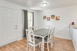 A dining area with a table and chairs, a white door, and a wall with framed pictures. - Walk to Beach & Local Pool! Galveston Area Condo (Jamaica Beach)