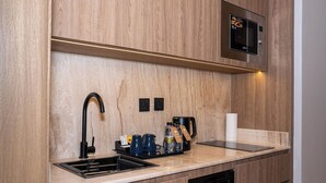 Une cuisine équipée d’un four à micro-ondes encastré, d’un évier avec un robinet et d’une machine à café.