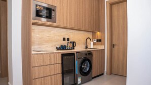 Une cuisine compacte équipée d’un four à micro-ondes encastré, d’une machine à café et d’un lave-linge.