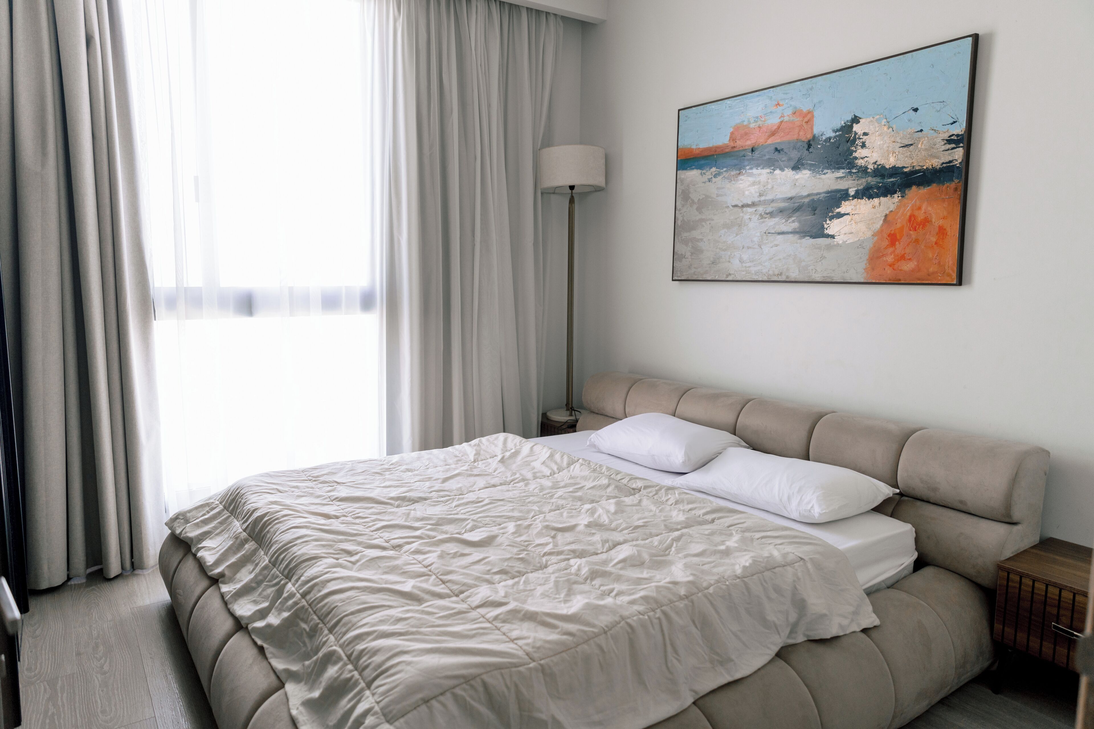 Ett modernt hotellrum med en stor säng, en sänglampa och en tavla på väggen.