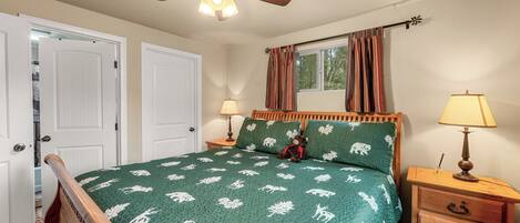 A bedroom with a bed, two bedside tables, a ceiling fan, and a window with curtains.