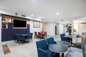 Eine moderne Hotellobby mit blau und rot gestalter Möbeln, einem großen Fernseher und einer Wanddekoration mit Muster.