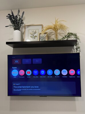Ein Fernsehbildschirm zeigt einen Startbildschirm mit verschiedenen App-Symbolen, darunter Netflix und YouTube.