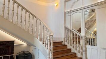 Un grand escalier avec des balustrades blanches et des marches en bois, menant à l’étage supérieur.