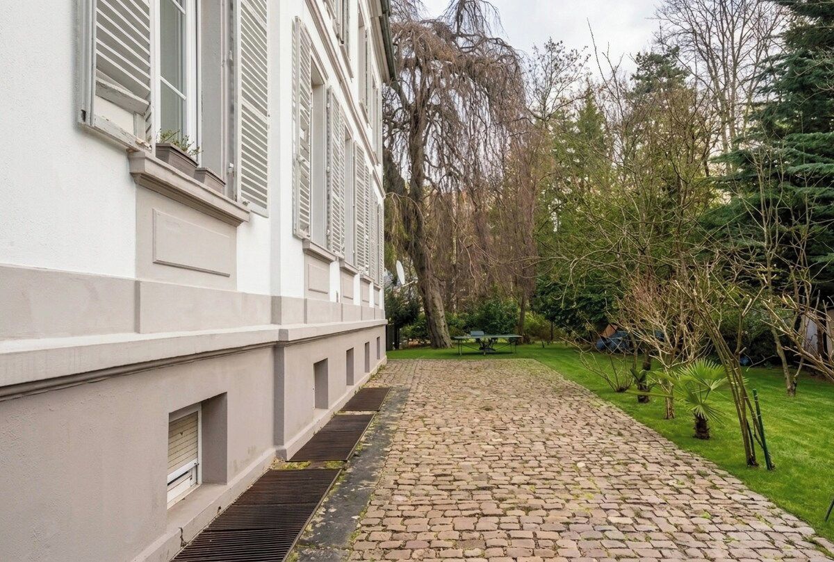 Un sendero adoquinado que lleva a un edificio con paredes blancas y contraventanas.