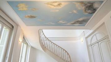 Una escalera en espiral con un techo pintado que representa nubes.