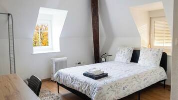 Un dormitorio con cama, escritorio, radiador y ventana.