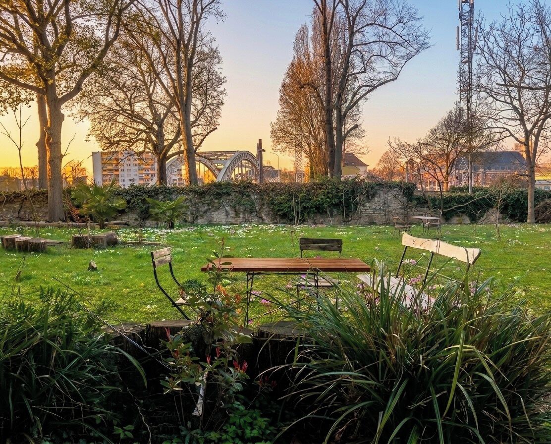 Un parc avec un banc en bois, un mur de pierre et des arbres.