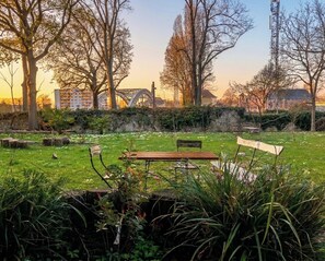 Een park met een houten bankje, een stenen muur en bomen.