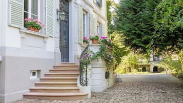 A cobblestone street leading to a building with a set of stairs and a flower box with pink flowers.
