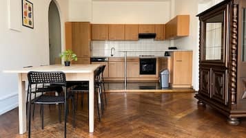 A modern kitchen with wooden cabinets, a dining table with chairs, and a herringbone floor pattern.