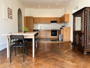 Een moderne keuken met houten kasten, een eettafel met stoelen en een visgraatvloer.