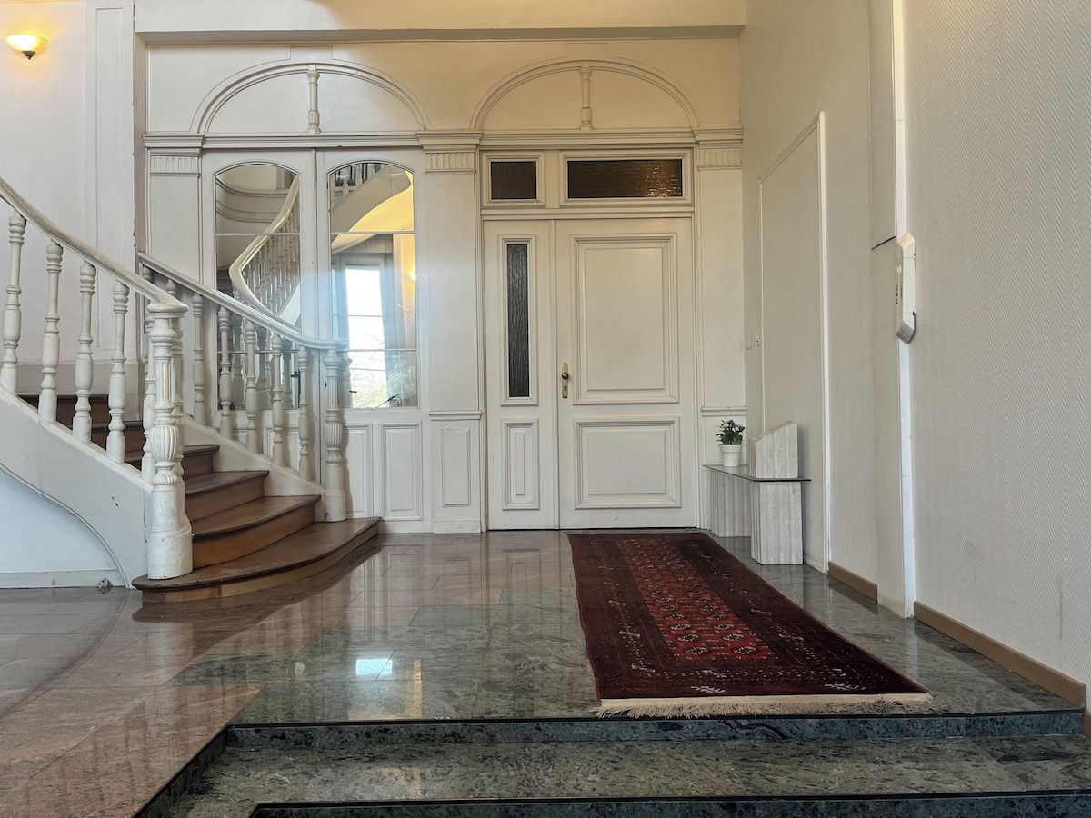 A grand entrance with a marble staircase, a red carpet, and a white door with glass panels.