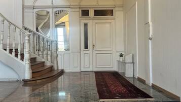 A grand entrance with a marble staircase, a red carpet, and a white door with glass panels.