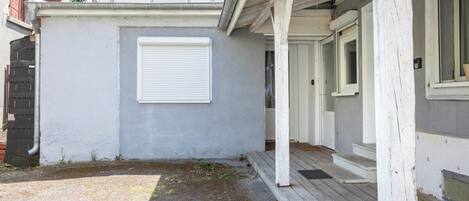 A residential property with a grey exterior, a white door, and a wooden deck.