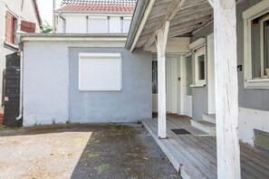 Een woonhuis met een grijze gevel, een witte deur en een houten terras.