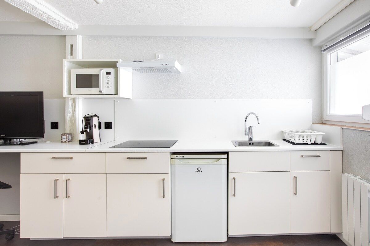 Una cocina moderna equipada con microondas, cafetera, lavavajillas y un lavabo.