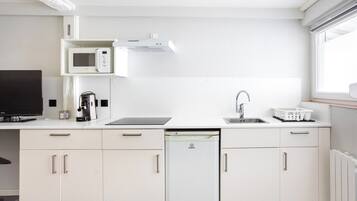 Una cocina moderna equipada con microondas, cafetera, lavavajillas y un lavabo.