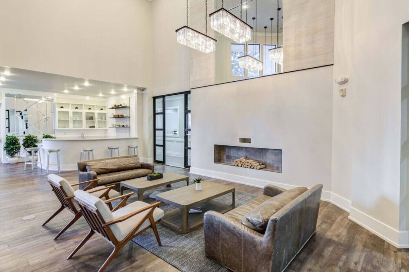 A spacious living area with a fireplace, modern furniture, and a kitchen in the background.
