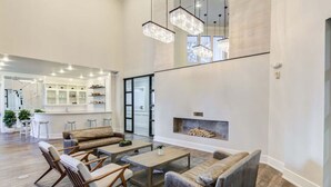 A spacious living area with a fireplace, wooden furniture, and a kitchen in the background.